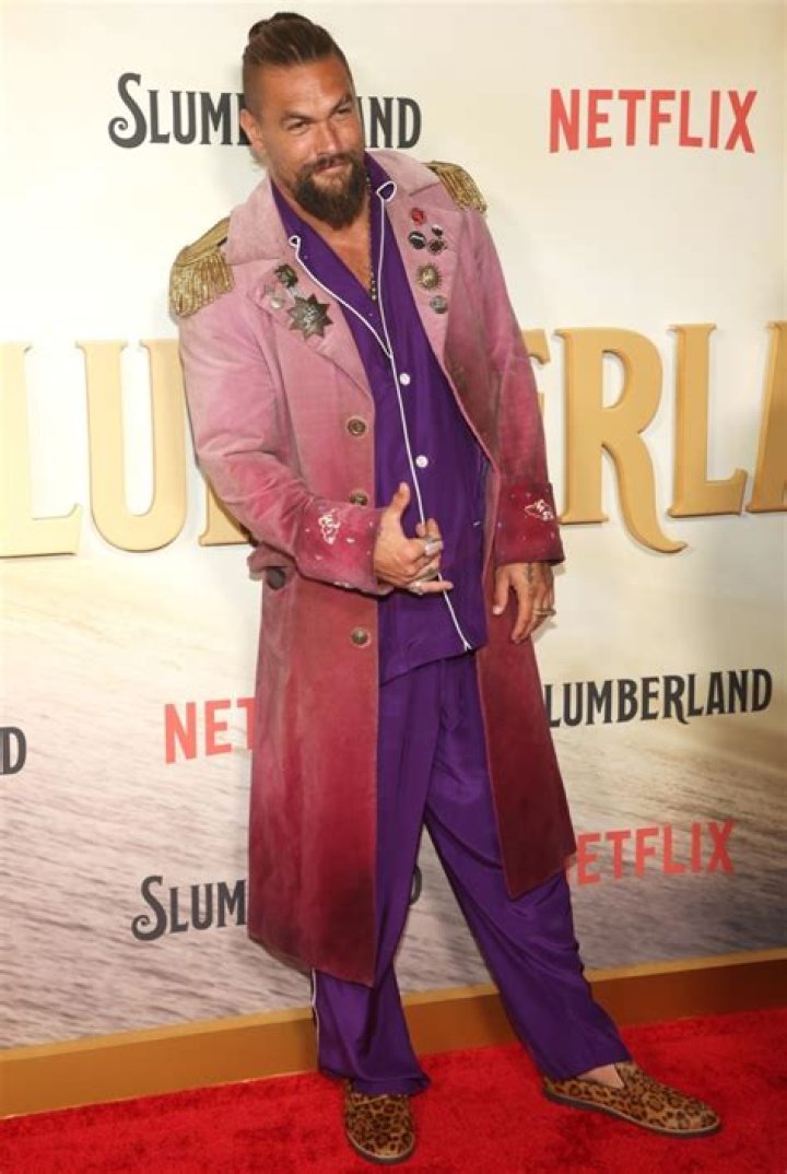 Jason Momoa all smiles in a pink jacket and purple pajamas at Netflix’s Slumberland premiere